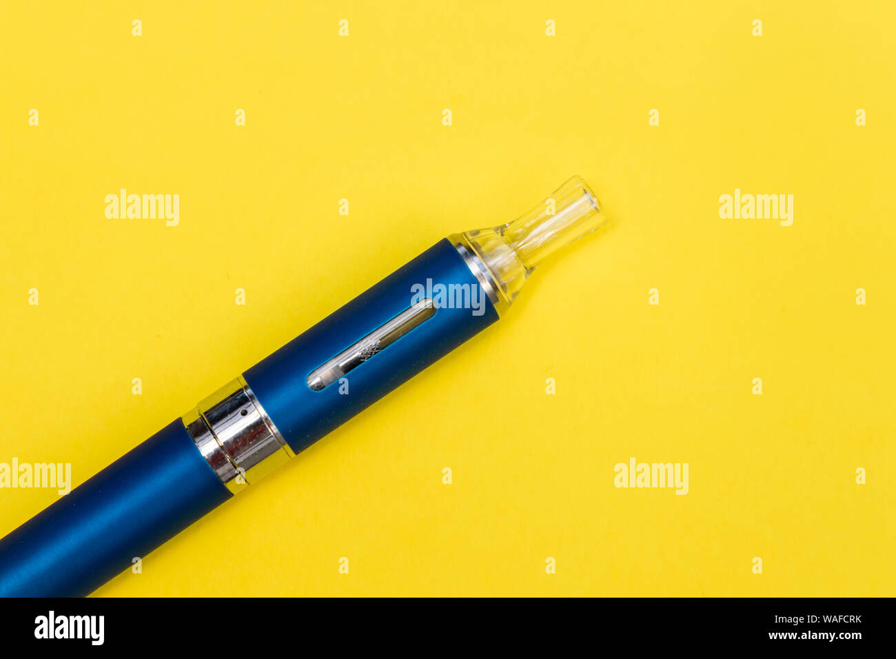 Vape pen metal electronic cigarette with vaping yellow background Stock Photo