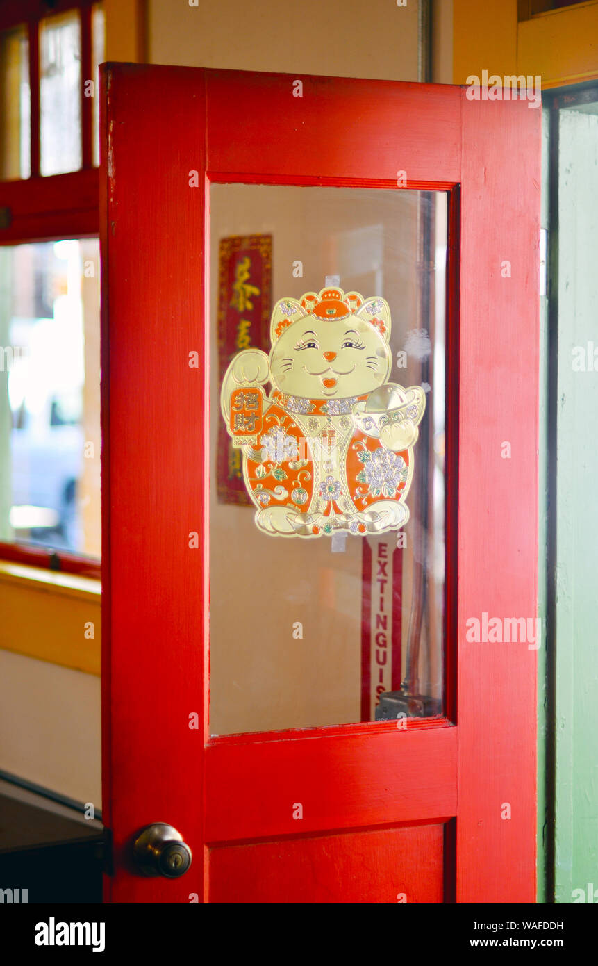 Red half glazed entrance door to the Locke museum with Chinese lucky waving cat mounted on the glass Stock Photo