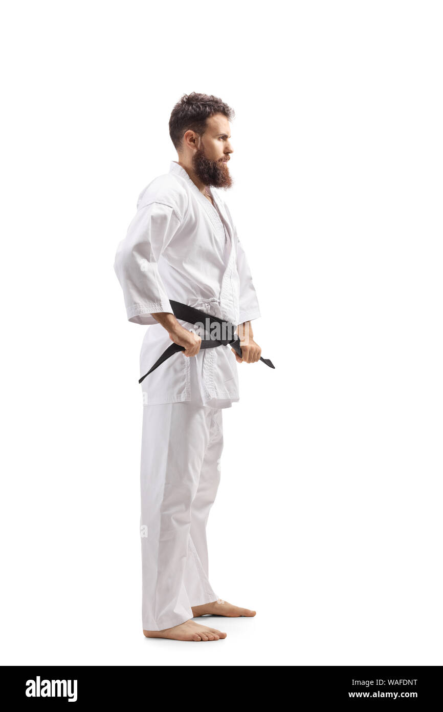 Full length profile shot of a bearded man in kimono tying his black belt isolated on white background Stock Photo