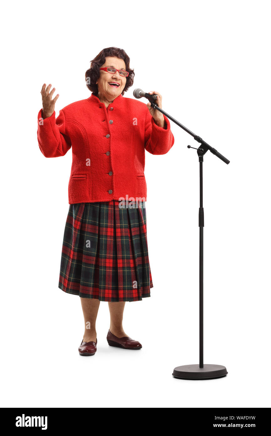 Full length portrait of an older lady in a red coat singing on a microphone isolated on white background Stock Photo