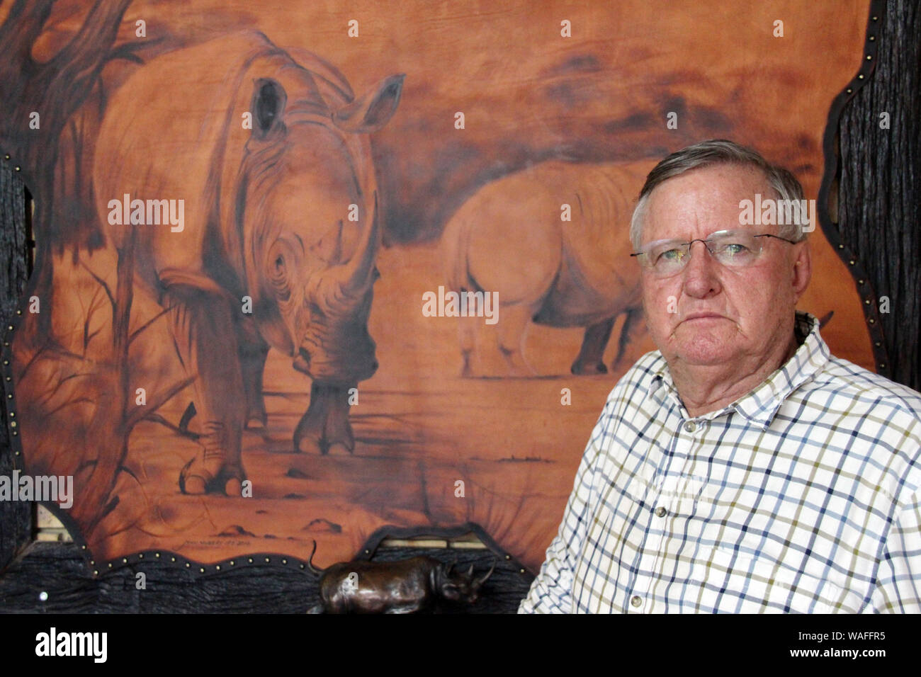 08 February 2019, South Africa, ---: John Hume, owner of the private rhino breeding farm in South Africa's Northwest Province, stands in front of a rhino painting in the office of his rhino breeding farm. His farm in South Africa's Northwest Province is home to more than 1700 white rhinos. International trade in rhinoceros horns is prohibited. But in Asia, especially in Vietnam and China, horn is popular as an ingredient of traditional medicine and costs about as much as gold. This has led to a boom in poaching, although the horns consist mainly of keratin - like human fingernails. But the sup Stock Photo