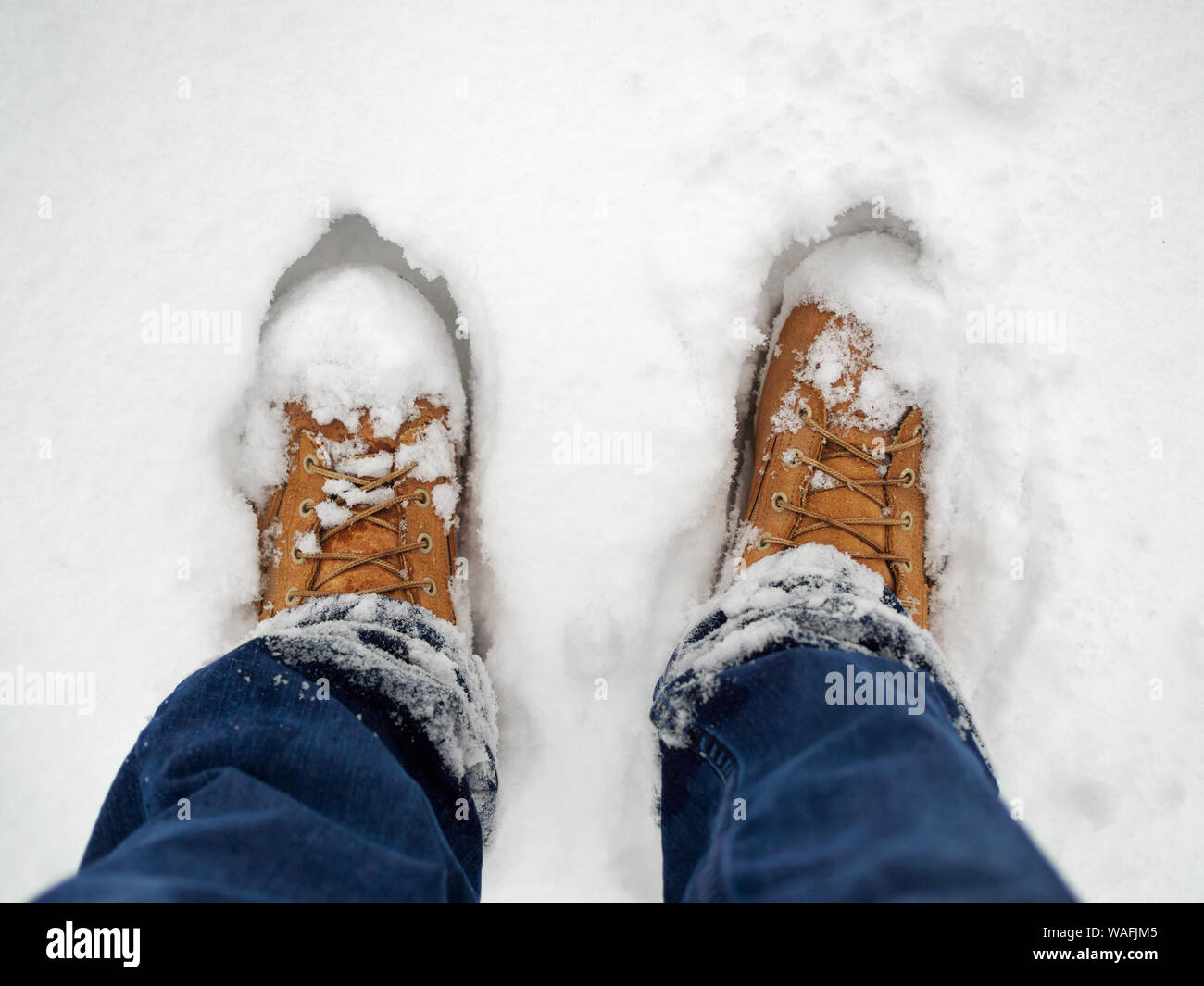 Man standing in yellow boots in snow, low section Stock Photo