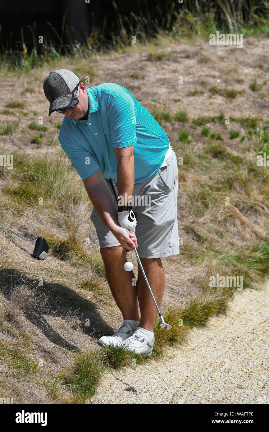 Golfer Hitting a Tough Shot out of the Rough Behind a Sand Trap Stock