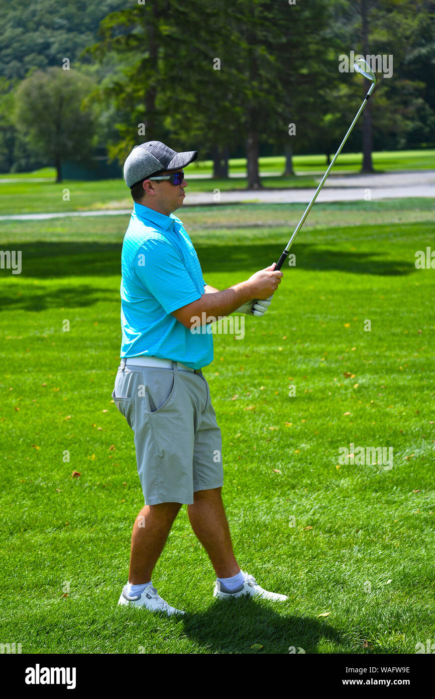 Young Man Looking Down the Fairway After Hitting a Golf Ball with an Iron. Stock Photo