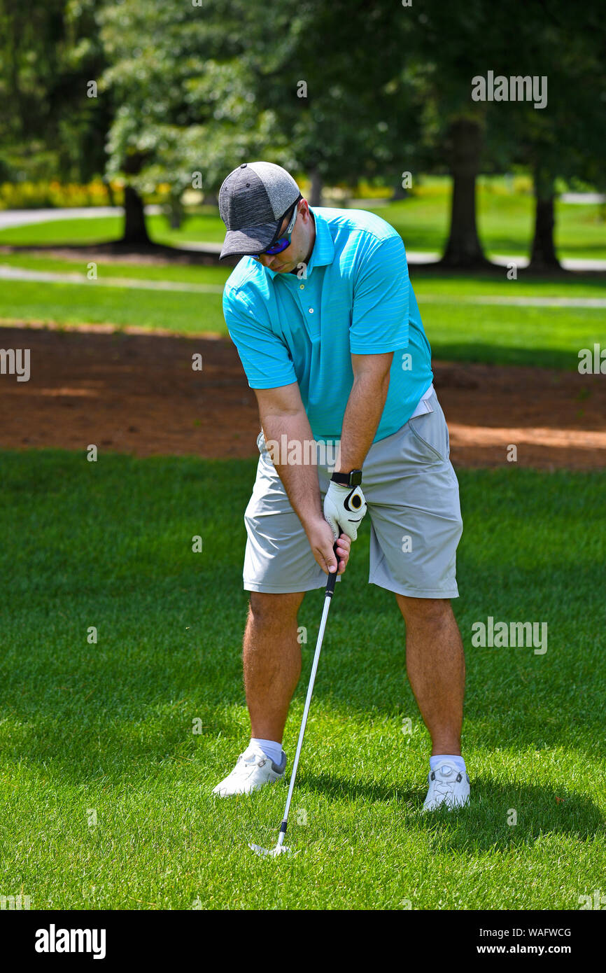 Young Man Looking Down in Preparation of  Hitting a Golf Ball Down the Fairway. Stock Photo