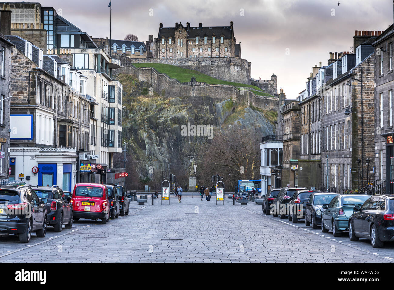 Cobbled street view looking towards the Statue of Thomas Guthrie on Princes Street with the Castle above Edinburgh Scotland Stock Photo