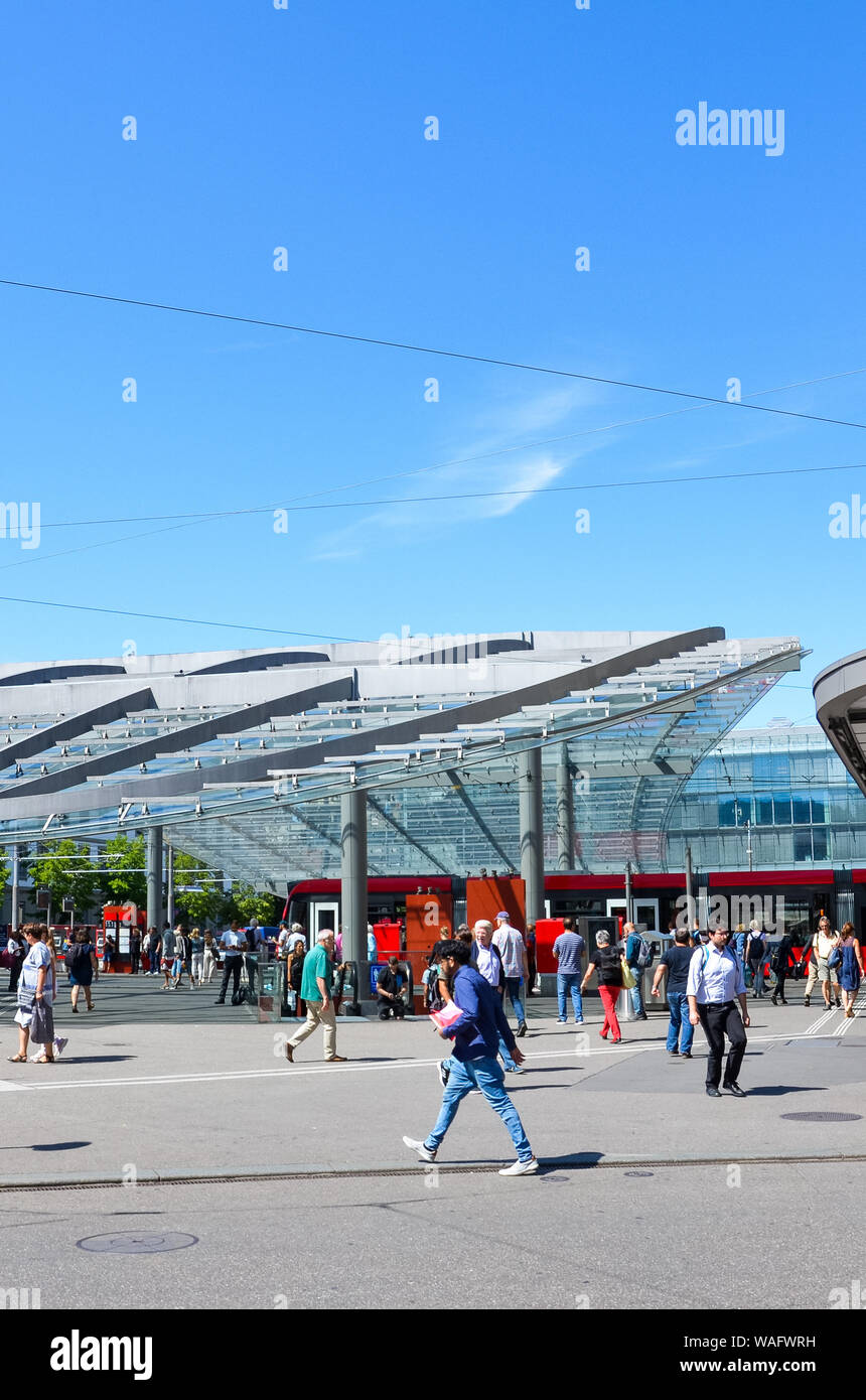 Bern, Switzerland - August 14 2019: People walking in the center of the Swiss capital near the main train station. Red tram in background. Public transport. Daily life. Sunny day. Vertical photo. Stock Photo