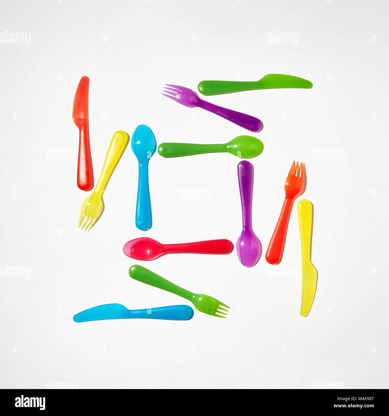 Set of plastic multicolored tableware on a light grey background with copy space. Top view. Stock Photo