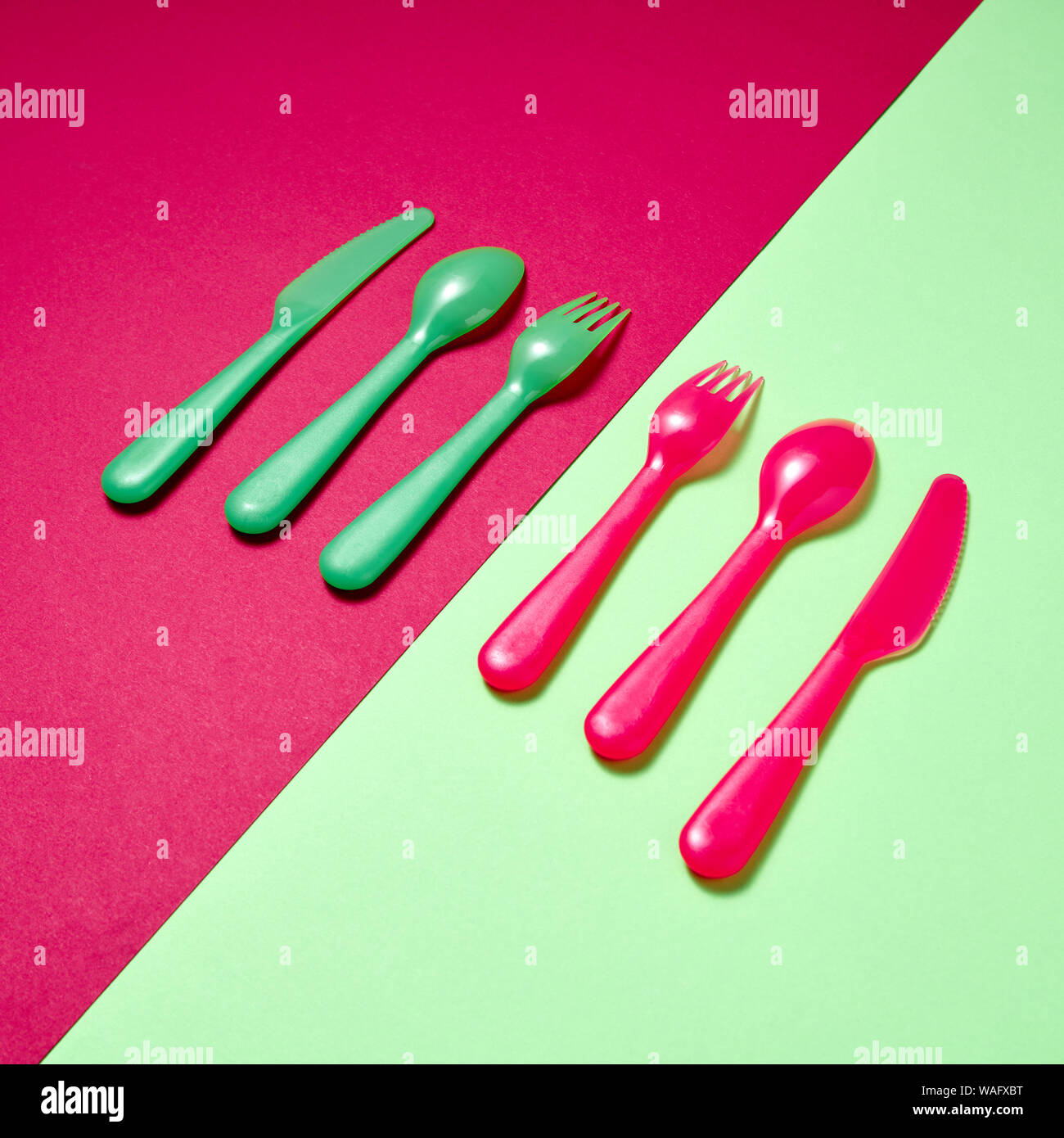 Diagonal pattern of plastic multicolored tableware on a duotone background with copy space. Stock Photo