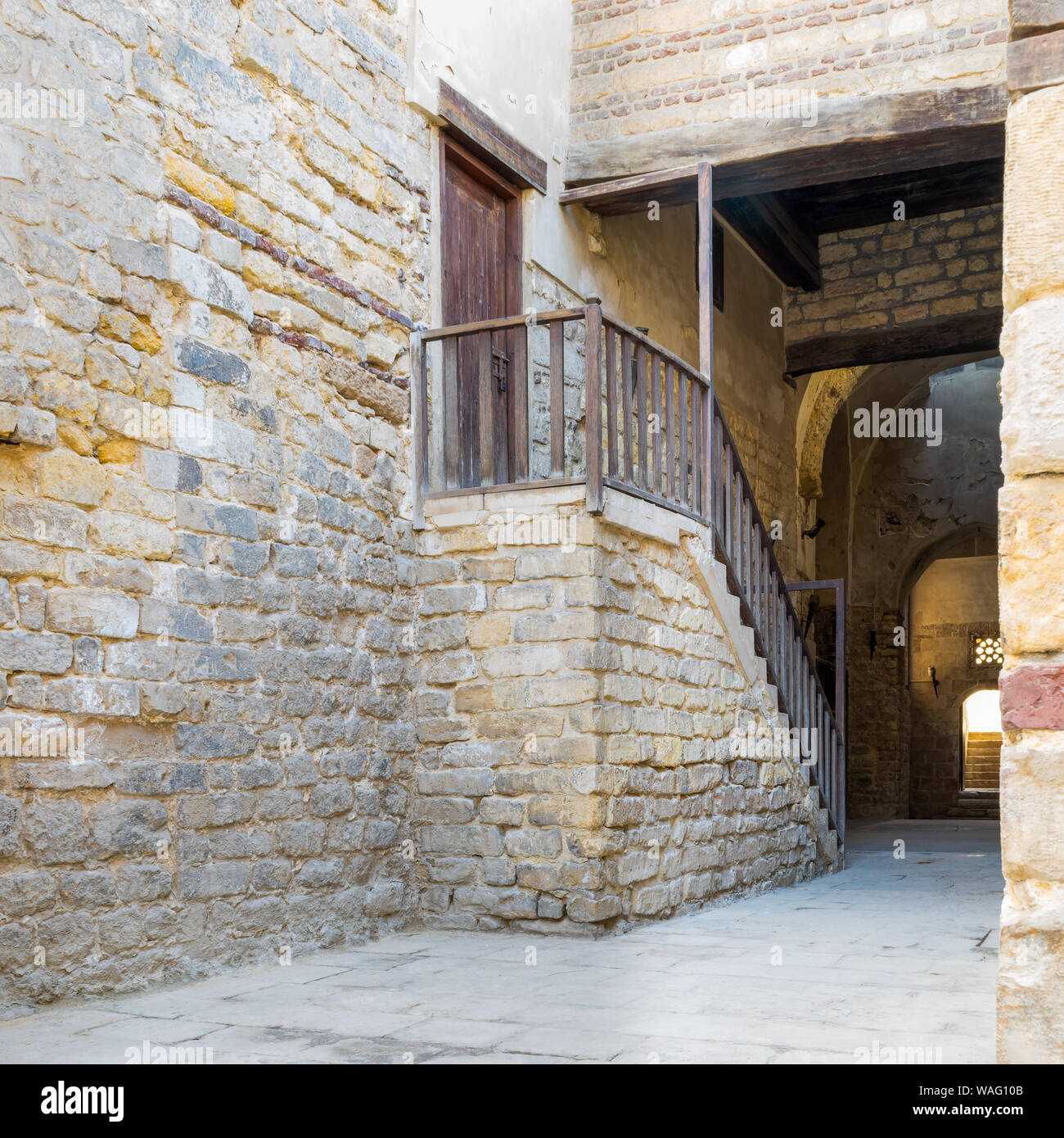 Exterior daylight shot of old abandoned staircase with wooden balustrade and wooden door at stone bricks passage surrounding Sultan Qalawun Complex located in Al Moez Street, Cairo, Egypt Stock Photo