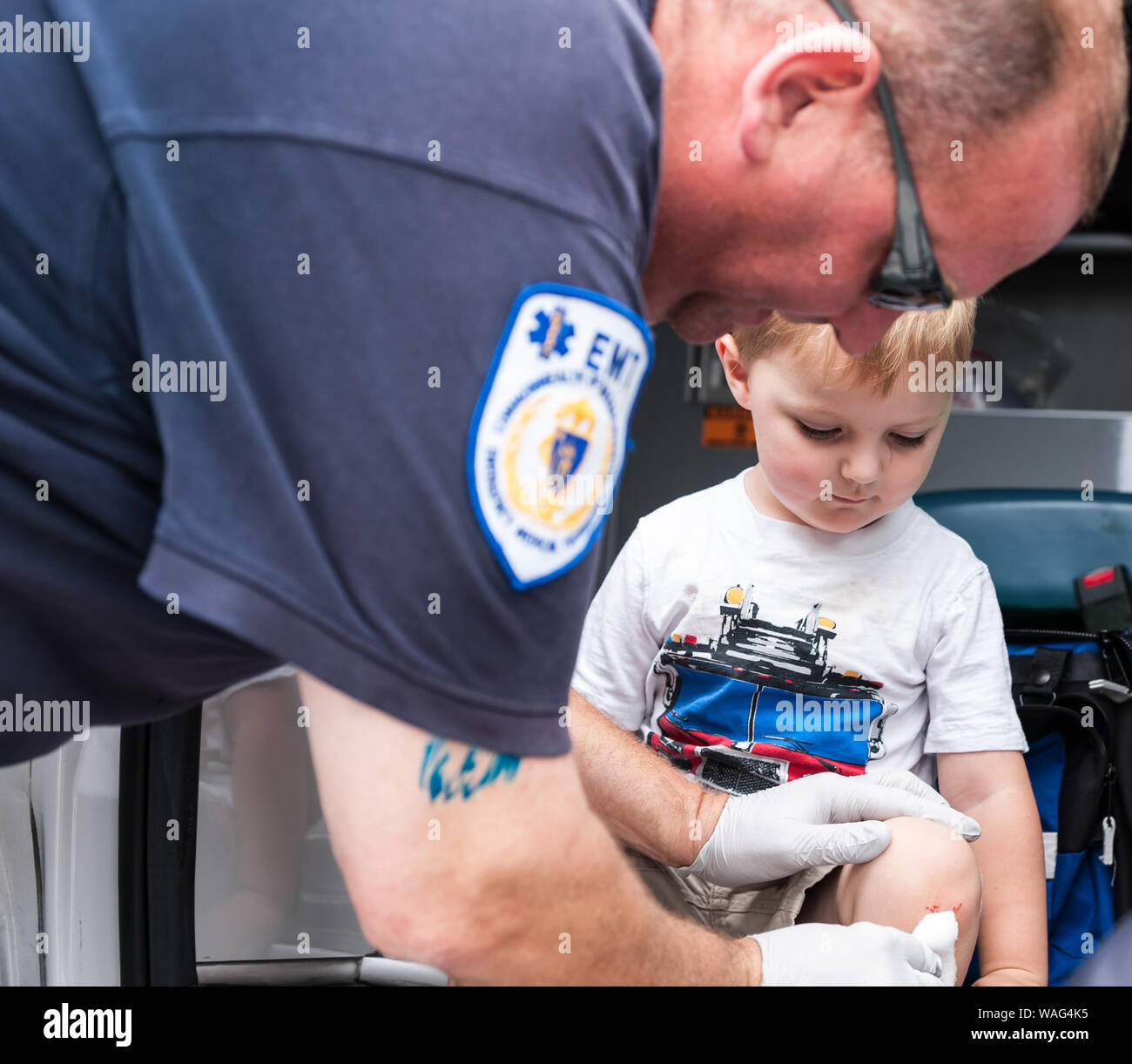 A very young boy at the Massachusetts Run for the Fallen, charity event to help Massachusetts military families, being helped by a local EMT. Stock Photo