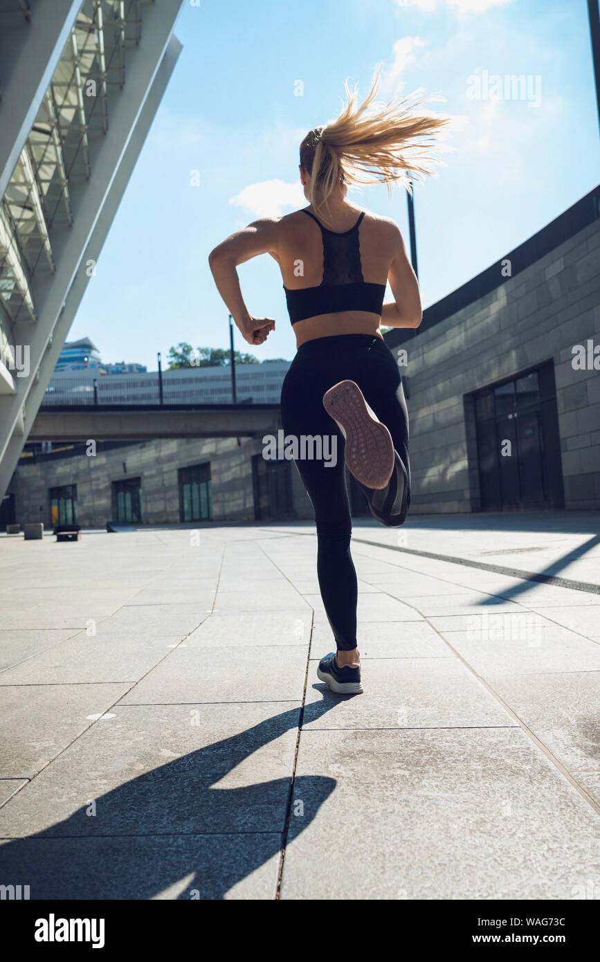 Blondie woman in black sportswear , trained legs during jogging Stock Photo  - Alamy