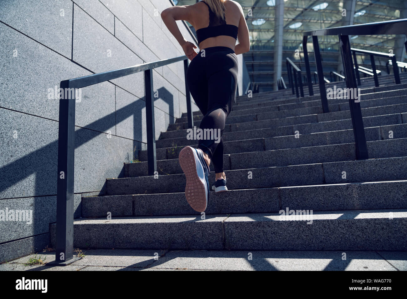 Strong athletic woman, trained legs during jogging on stairs Stock