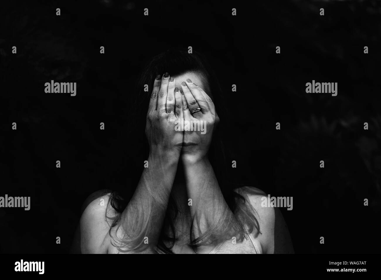 Double exposure portrait of female face hiding behind hands Stock Photo