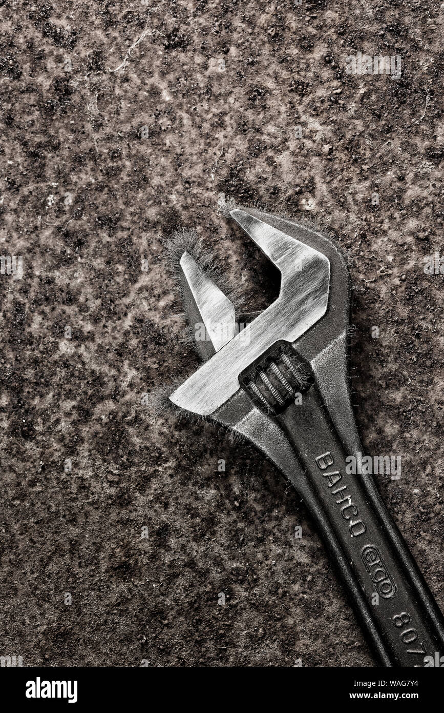 Wide jaw adjustable iron tempered metal spanner, wrench, covered in filings as its become magnetised, a nuisance Stock Photo