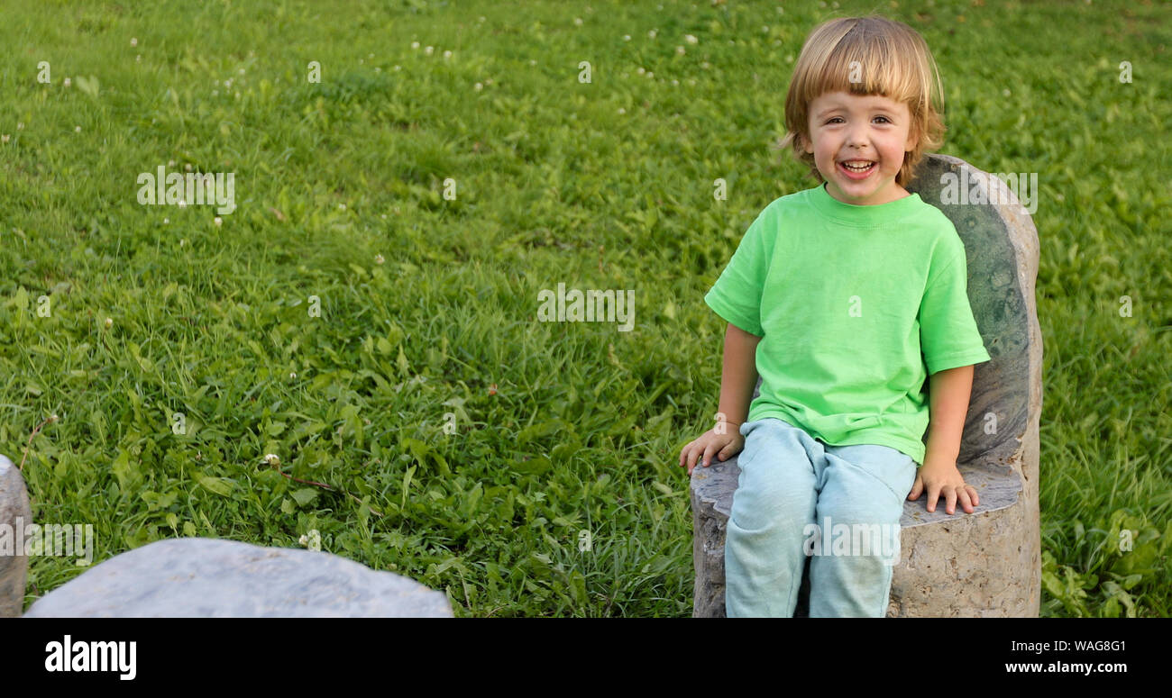 Child sitting on stone chair in park Stock Photo