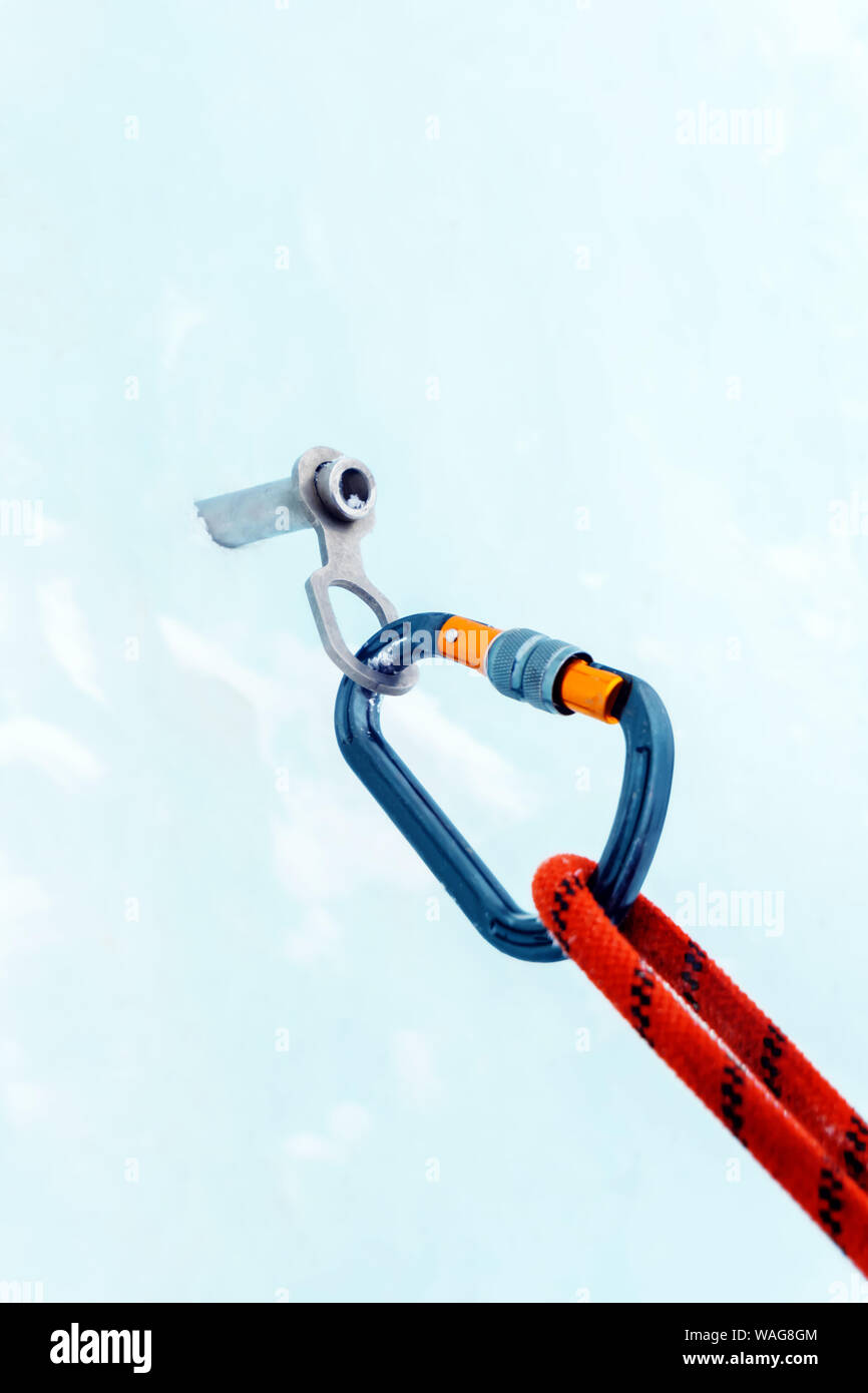 Ice climbing anchor with ice screw, safety rope and carabiner, closeup