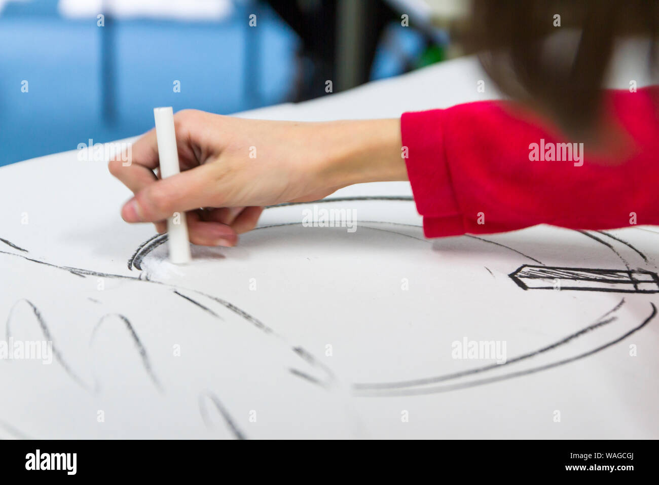 Primary school child drawing with a stick of white chalk, art class, uk Stock Photo