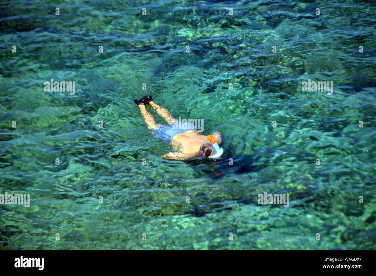 Man swimming underwater in a life jacket and a mask for snorkeling in Benidorm Island, Spain Stock Photo