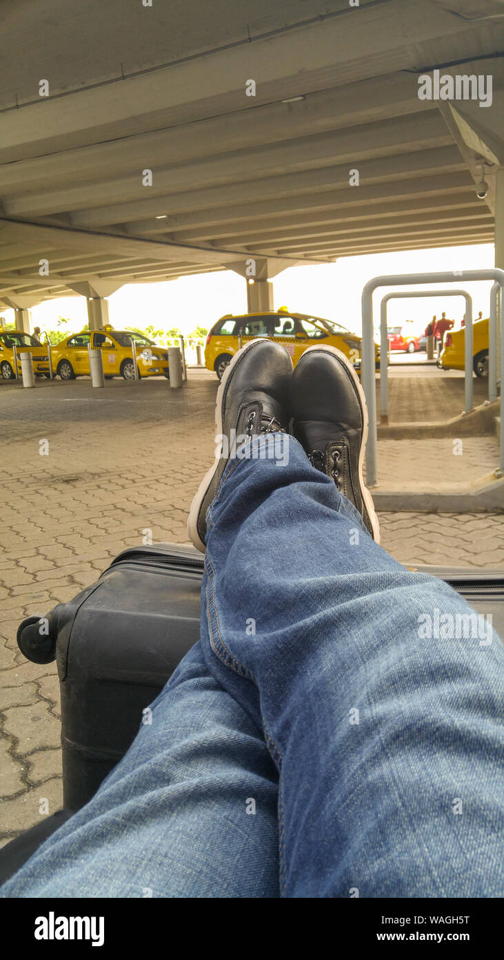 Man siting with his legs on his luggage in the airport parking lot waiting  for his connection Stock Photo - Alamy