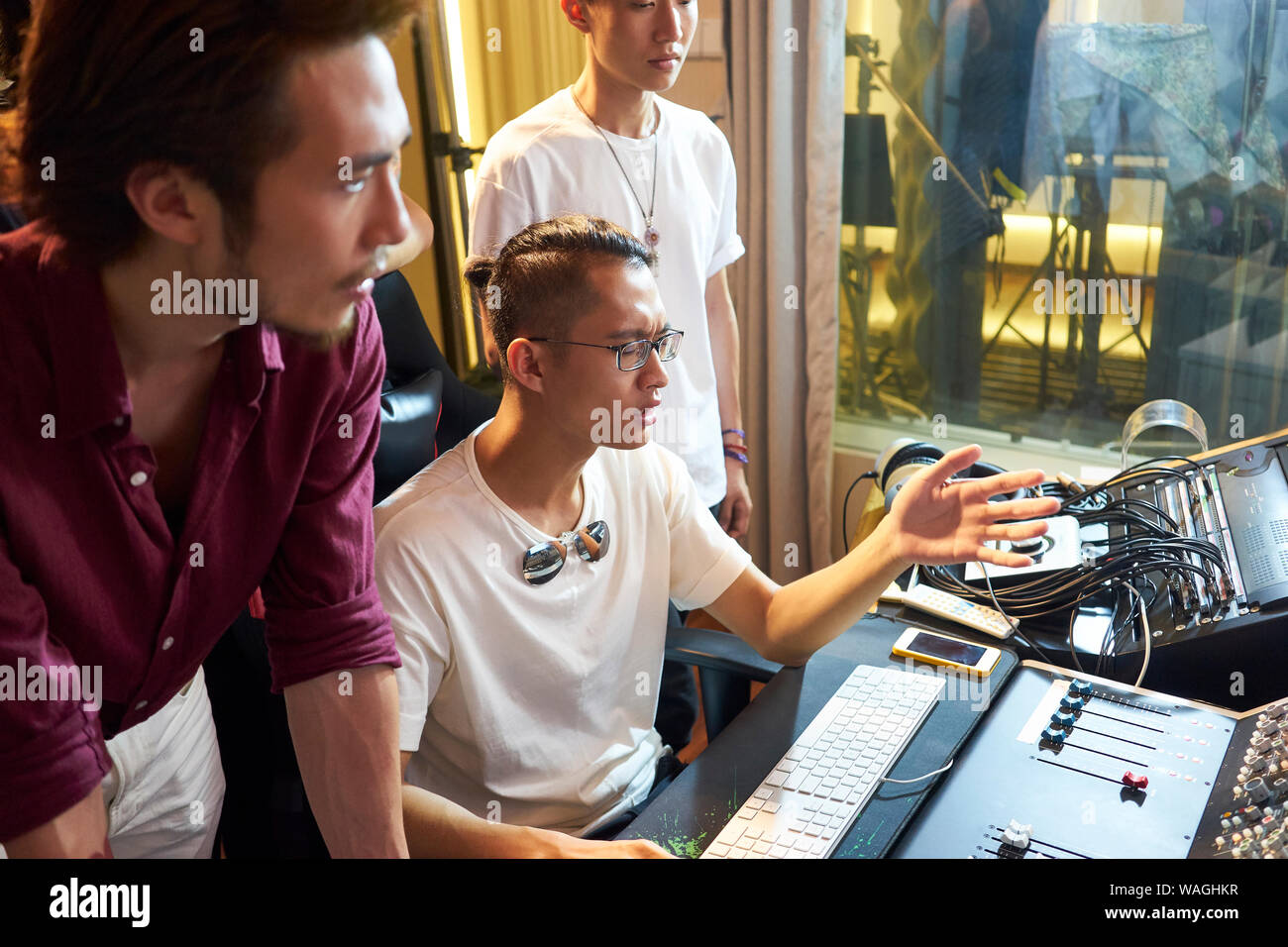 young members of an asian rock band working together editing music using computer Stock Photo