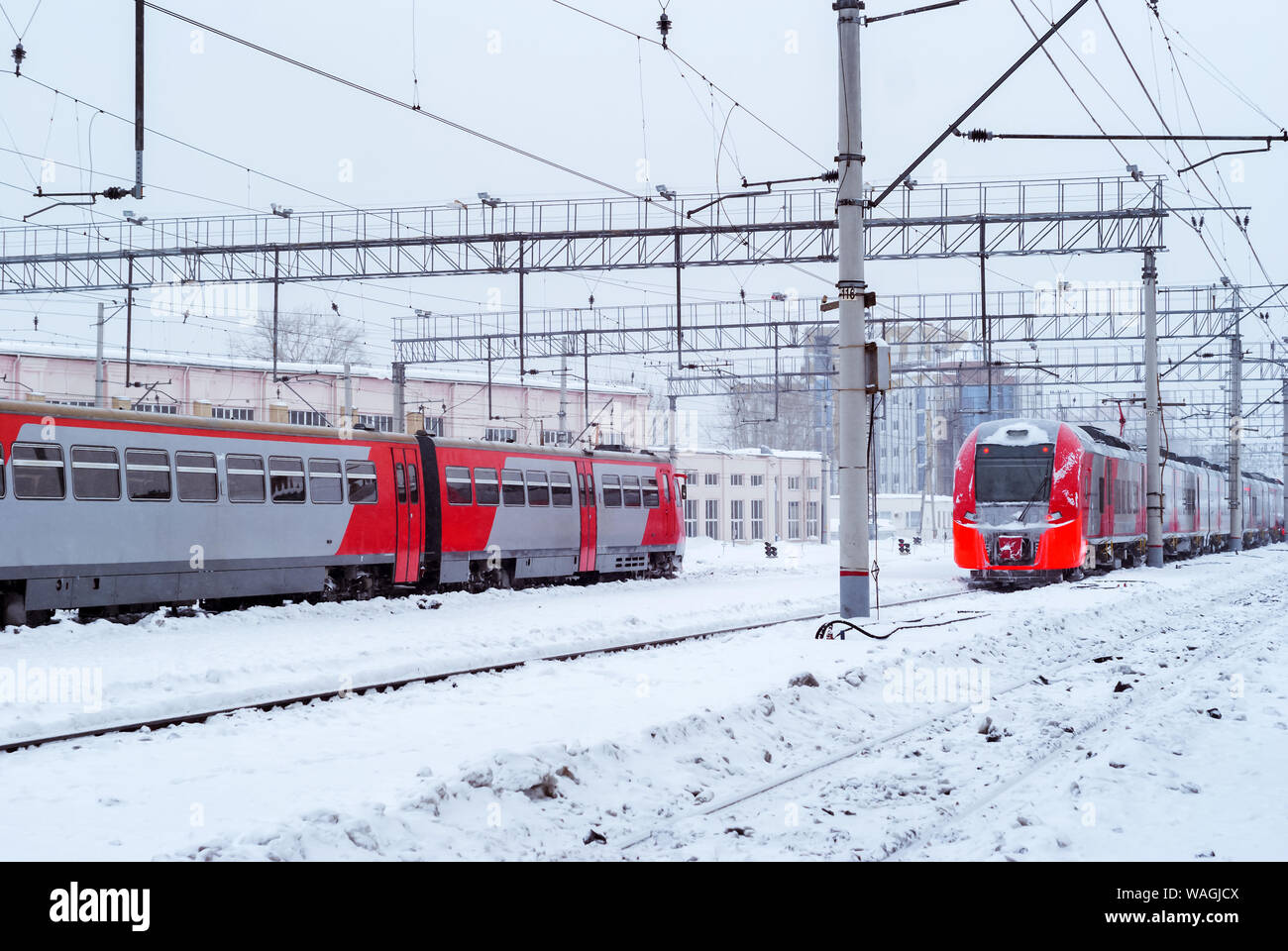 ice-covered diesel and electric multiple unit trains stand nearby at railway junction in winter Stock Photo
