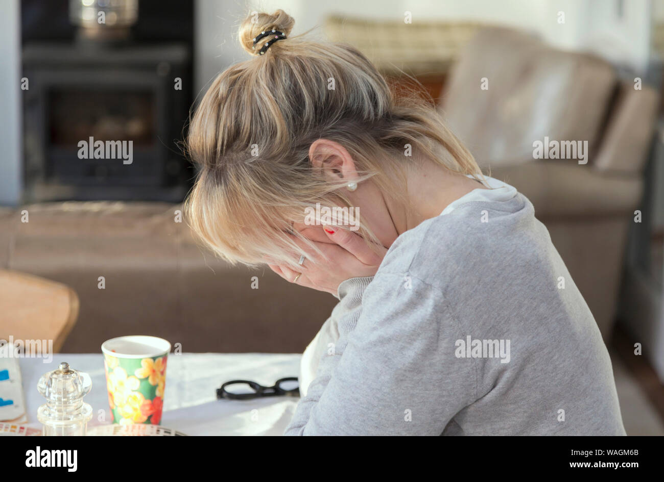 Unhappy young lady sitting with her head in her hands and covering her face. Stock Photo