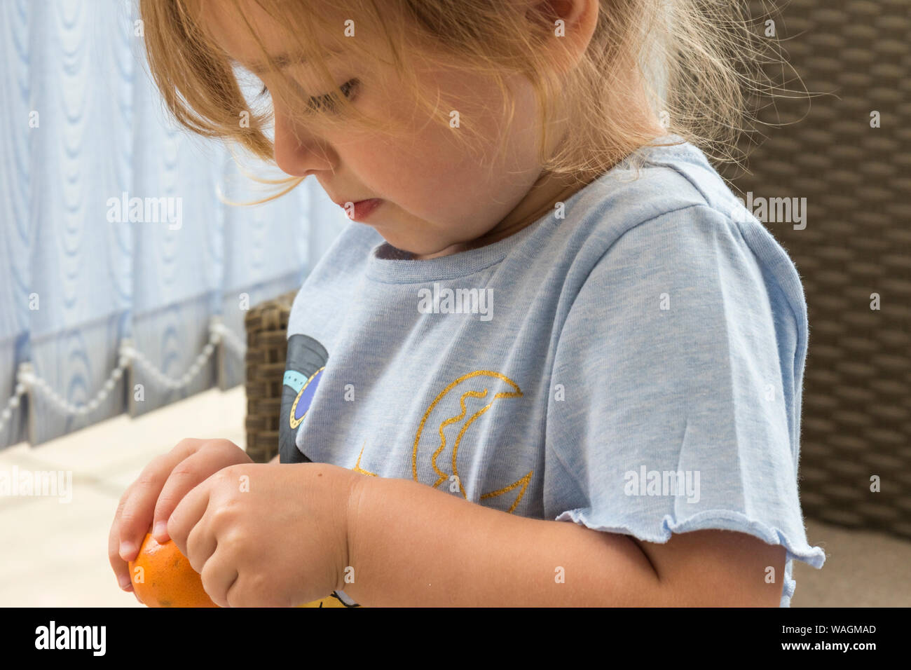 Close up portrait of a three year old girl wearing a grey top, trying