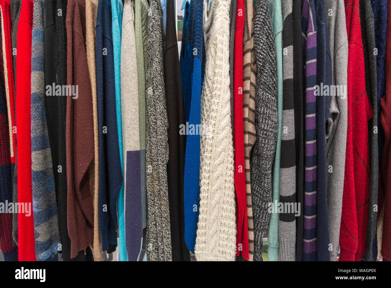 Row of knitted crocheted sweater and jumper hang on aluminium hanger