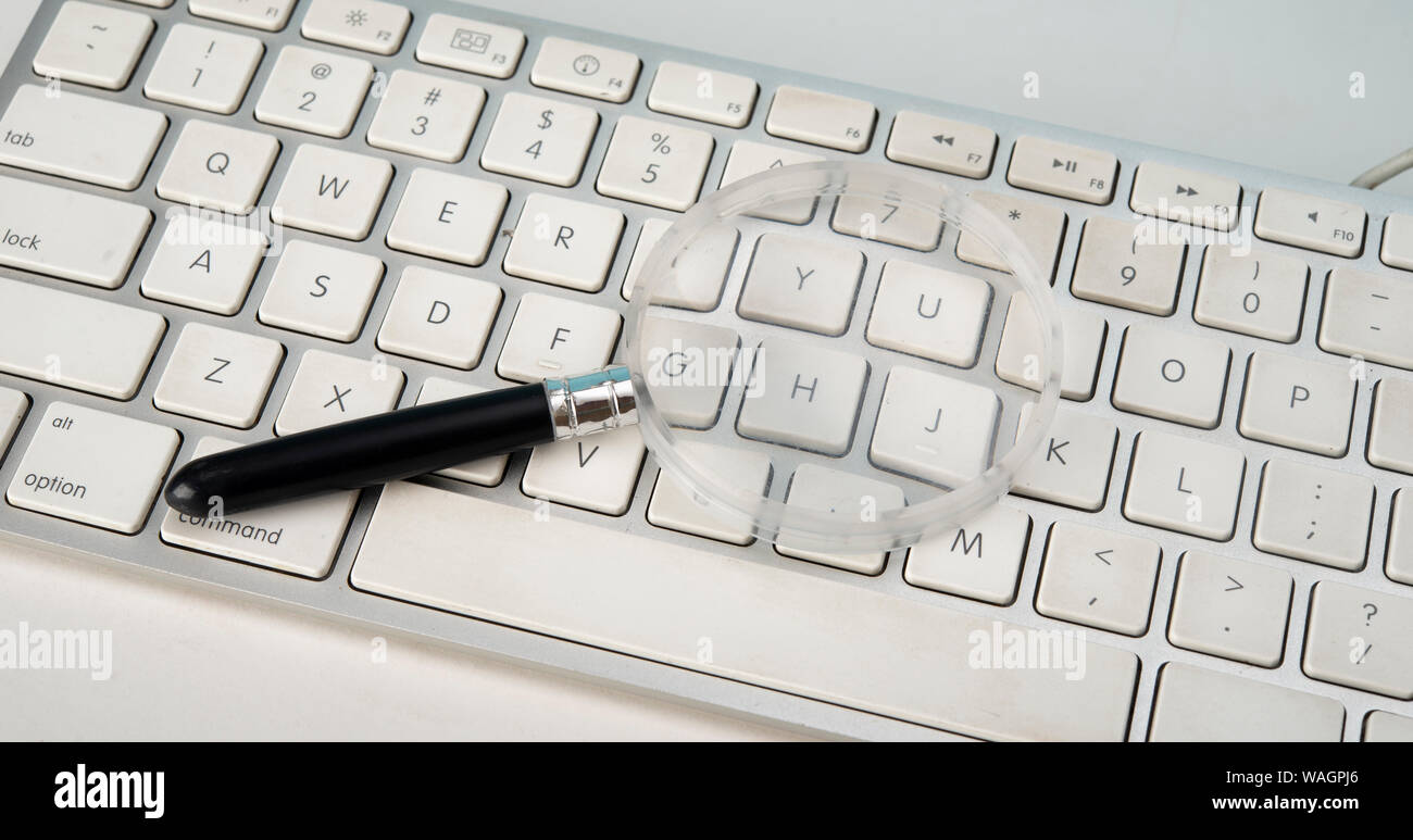 Magnifying glass tool on keyboard, online searching concept Stock Photo