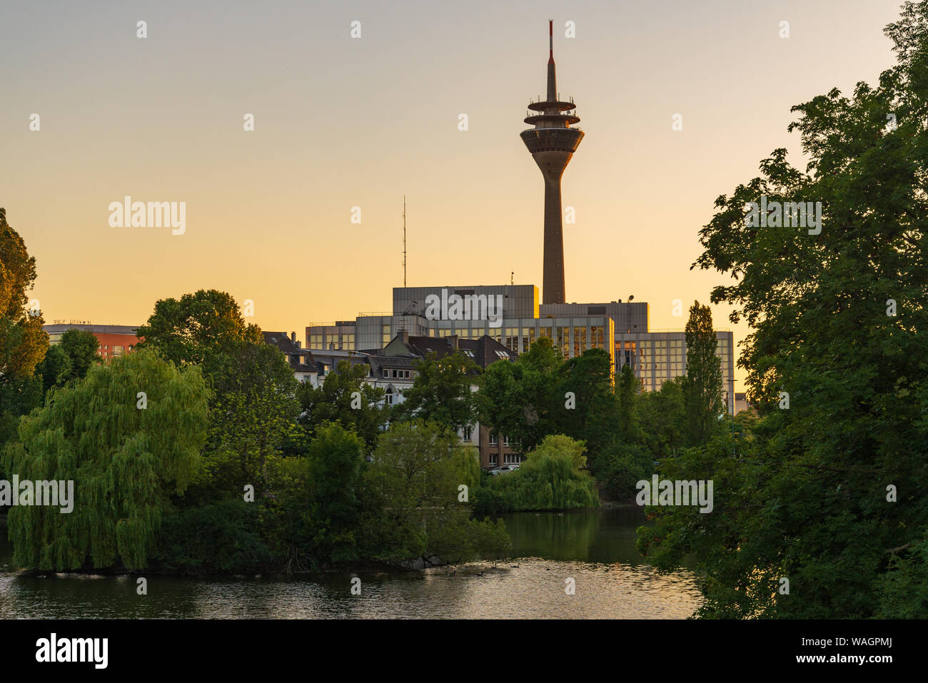 Outdoor silhouette view with twilight sky at Ständehaus park with reflection in the lake, and background of buildings and Rhine tower. Stock Photo
