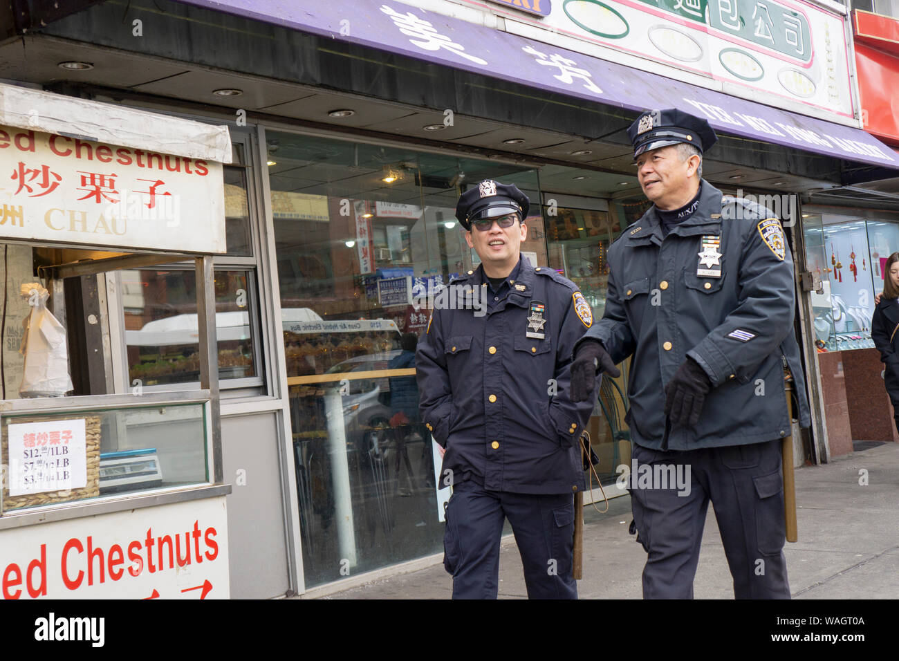 Two Asian American Auxiliary policemen walk down Main Street chatting. In Chinatown, Flushing, Queens, New York. Stock Photo