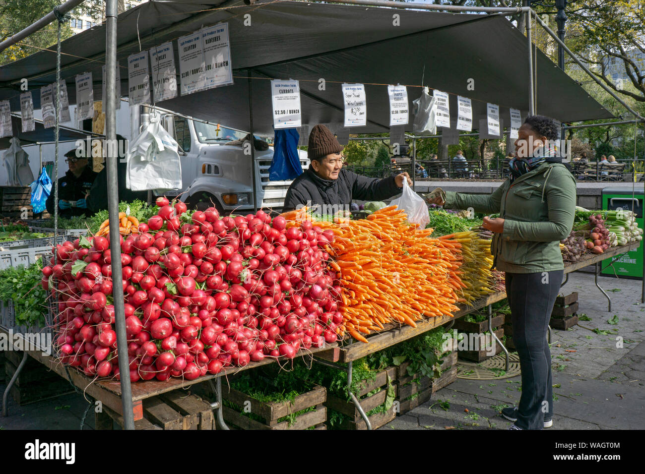 An Asian American man selling produce to an African American woman at he Union Square Green Market in Manhattan, New York City. Stock Photo