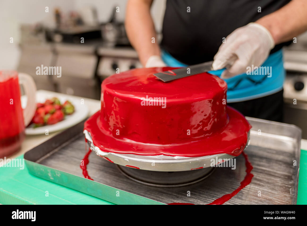 Male chef confectioner making a cake with a cherry. concept production process at home cakes to order customers. Stock Photo