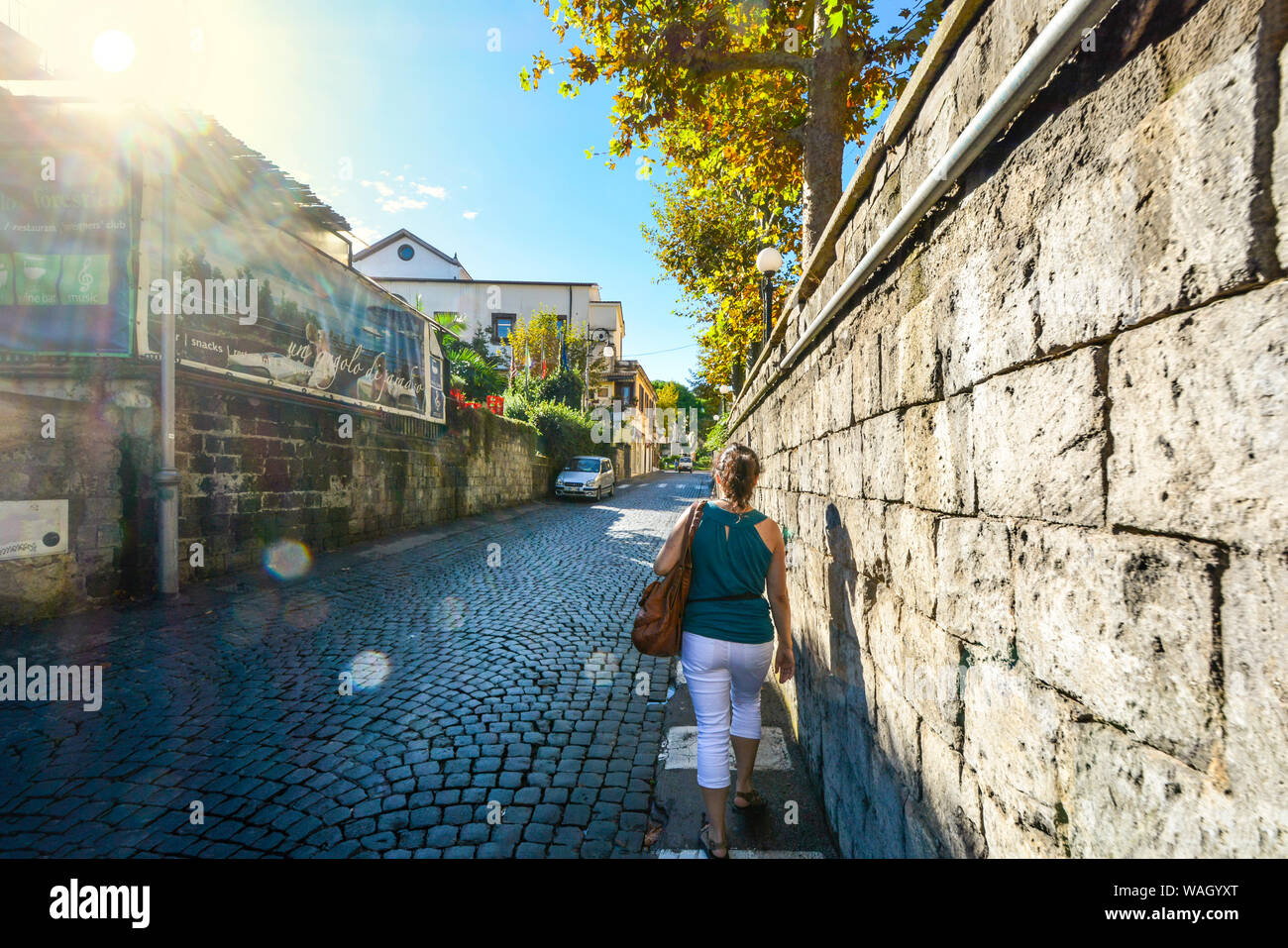 A young woman walks alone down a cobblestone back street in the resort town of Sorrento, Italy Stock Photo