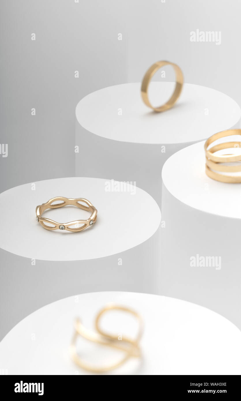 Modern Golden rings set on white cylinders Stock Photo