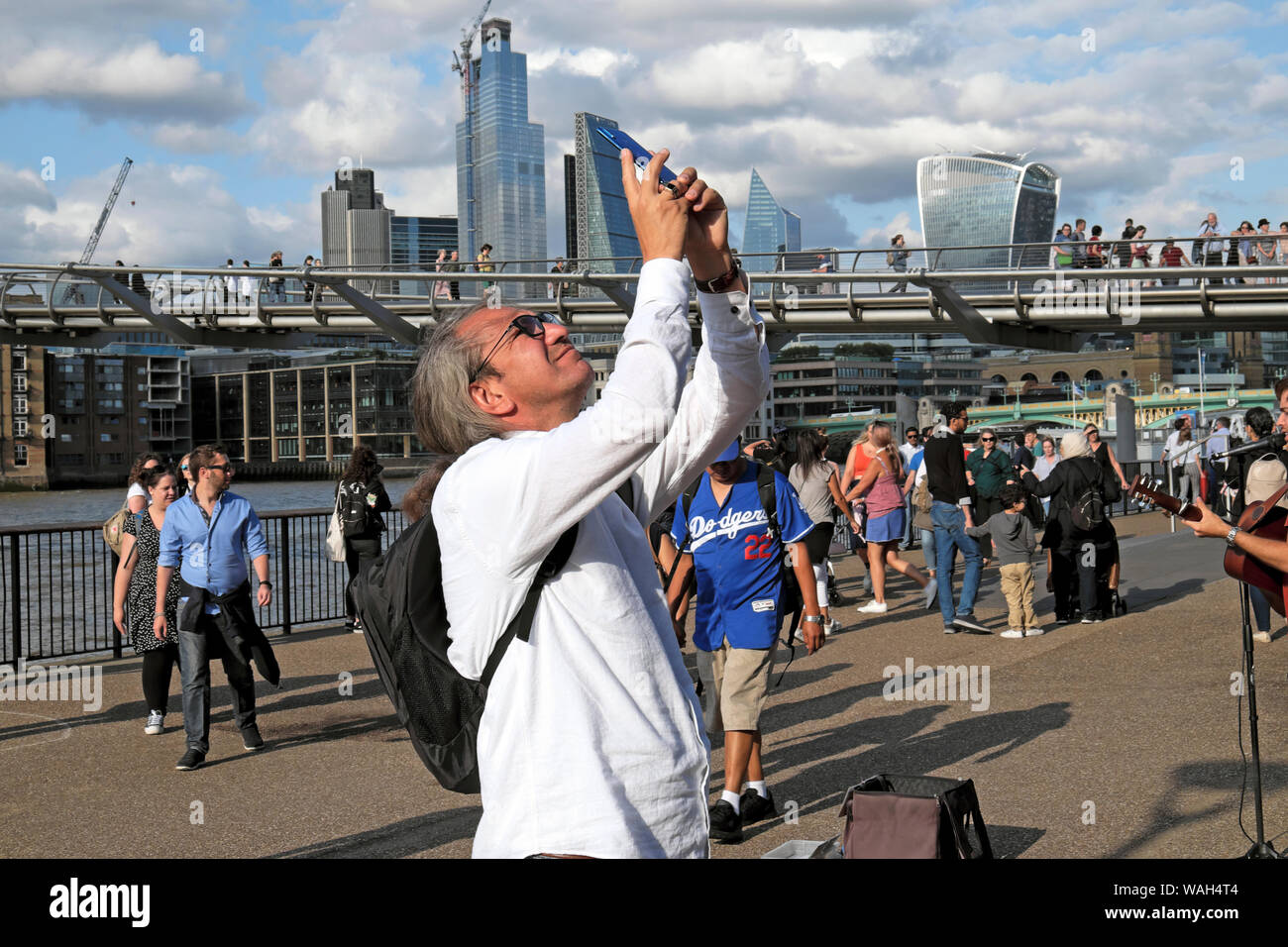 Tourist looking up taking mobile phone photo in street outside the Tate Modern Art Gallery Bankside in summer South London England UK  KATHY DEWITT Stock Photo