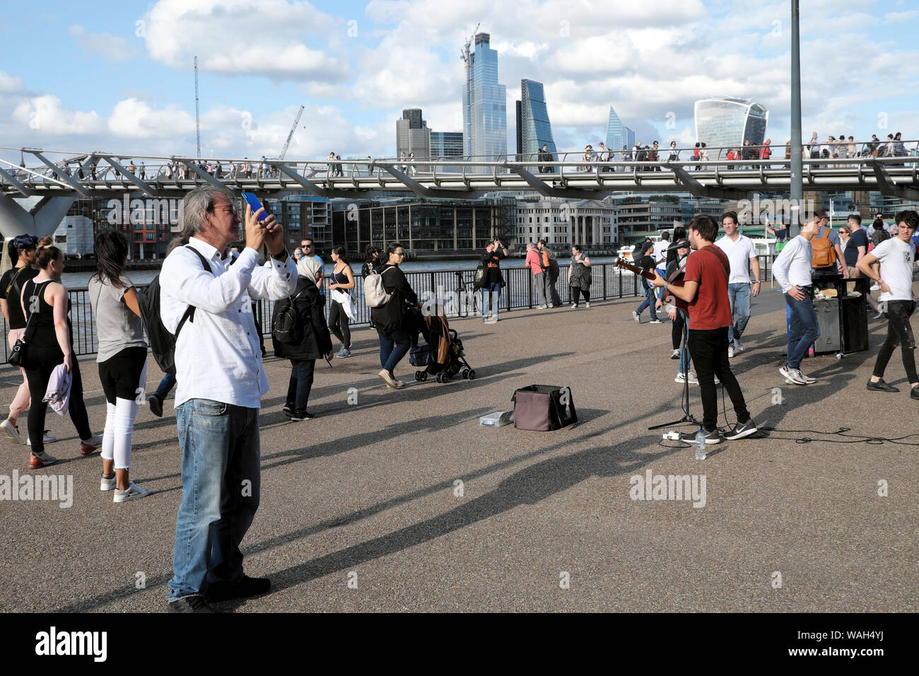 Busker busking & tourist  tourists in the street outside the Tate Modern Art Gallery Bankside by River Thames South London England UK  KATHY DEWITT Stock Photo