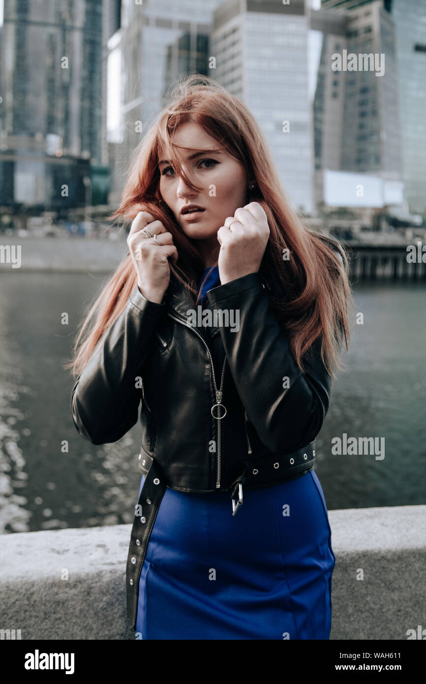 plus size woman with red hair wearing blue dress and leather black jacket Stock Photo