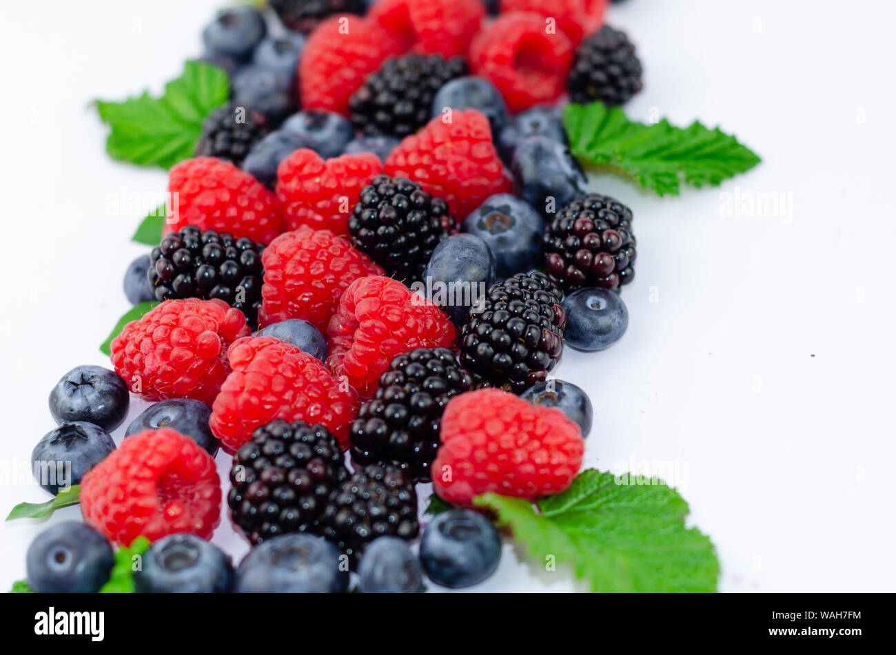 Blueberries, blackberries, raspberries and green leaves isolated on white. Stock Photo