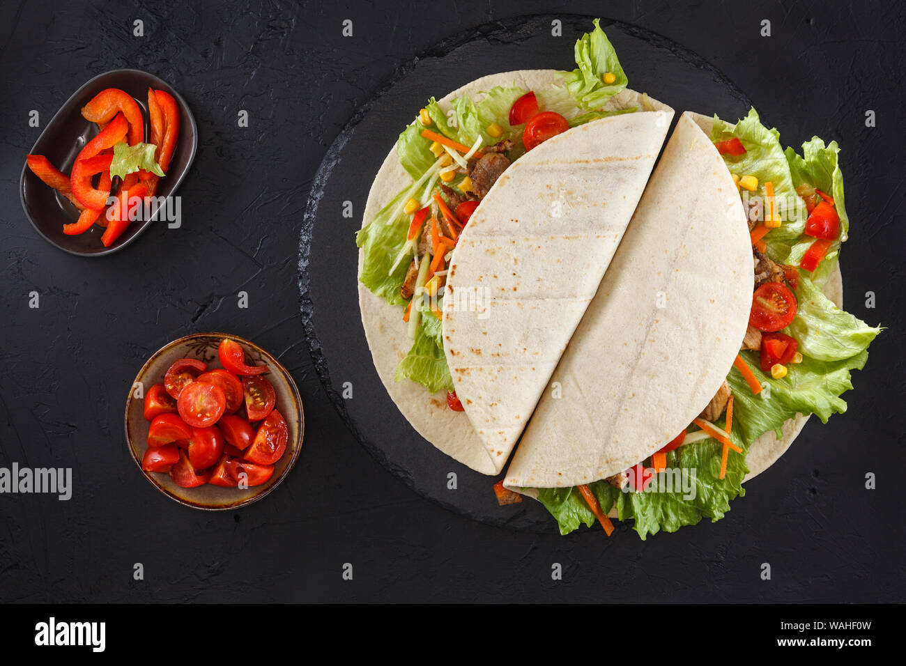 Burritos wraps with chicken and vegetables on black slate. Chicken