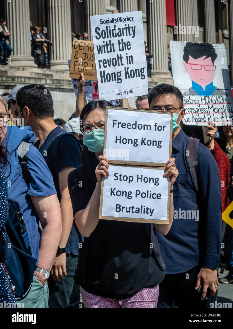 A female protester holding banners that state 'Freedom for Hong Kong' and 'Stop Hong Kong Police Brutality at the UK Solidarity with Hong Kong Rally. Stock Photo