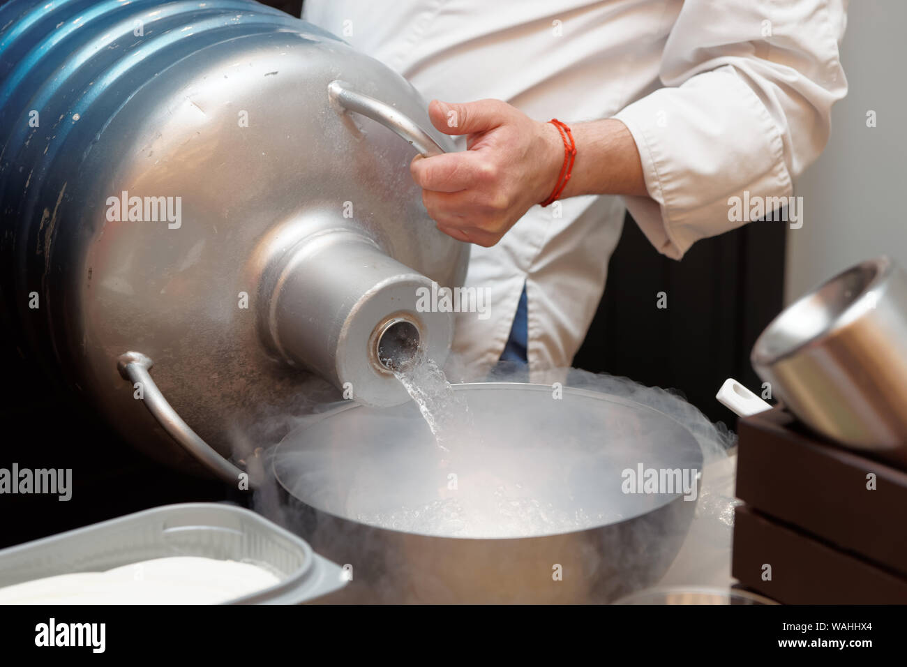 Chef is pouring liquid nitrogen from a large Dewar flask Stock Photo