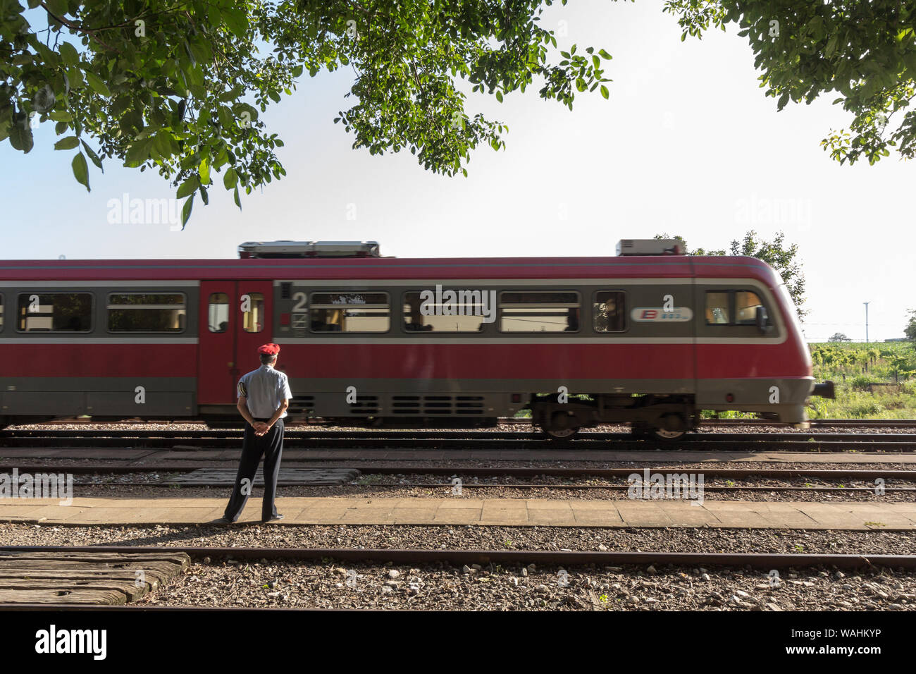 ALIBUNAR, SERBIA - JUNE 30, 2019: Regional DMU train passing by Alibunar train station being watched by a station master, a railworker in charge of ma Stock Photo