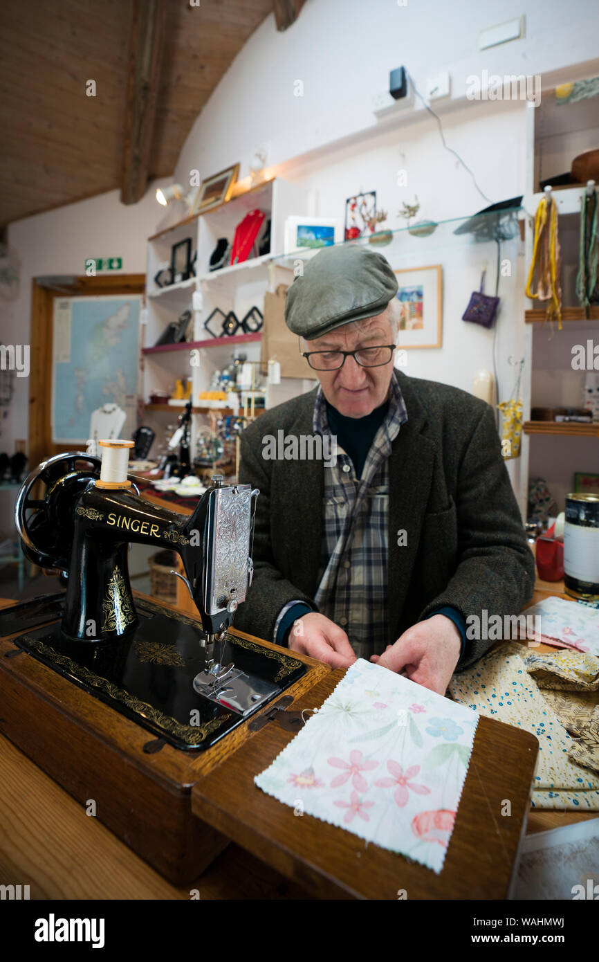 Scottish man, senior aged, sews pocket pouches on an antique Singer sewing machine in a tiny shop near the Iron Age broch at Carloway, Isle of Lewis, Stock Photo
