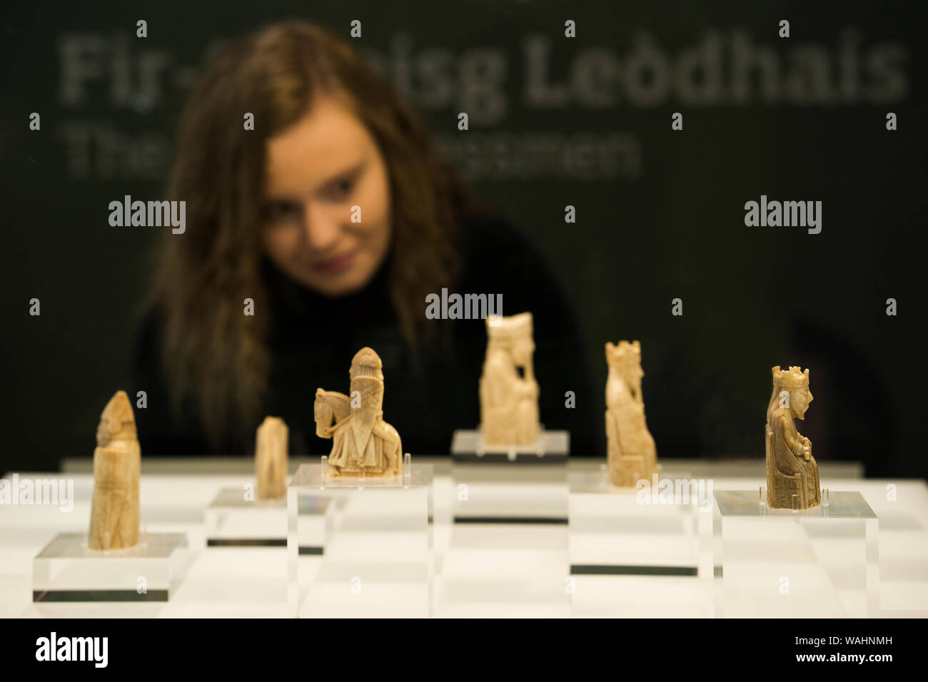 Teenage girl looks at the original chess pieces from an authentic chess set carved from walrus ivory that drifted from a shipwreck at sea were discove Stock Photo