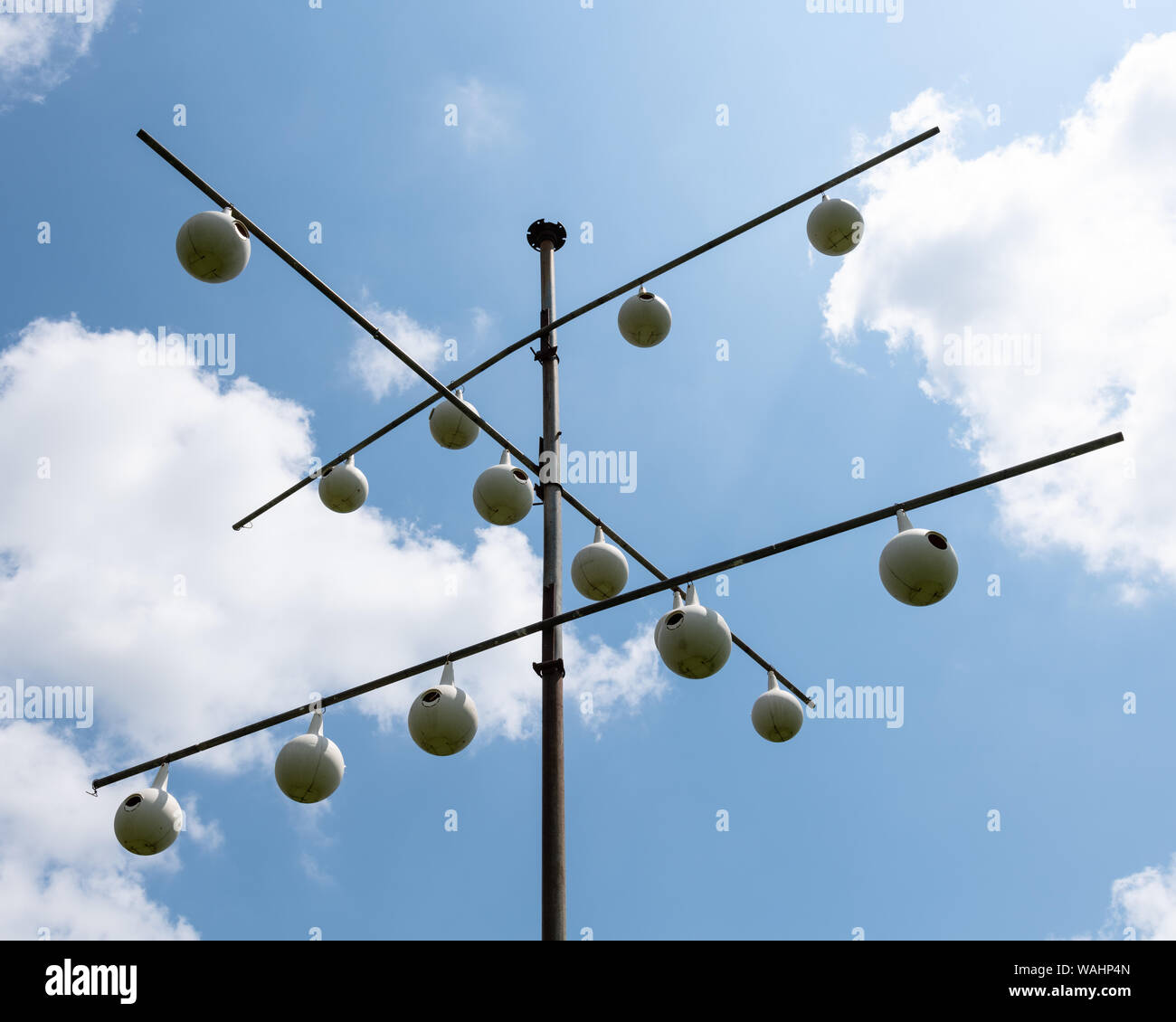 A purple martin gourd rack in front of a blue sky with white clouds. Stock Photo