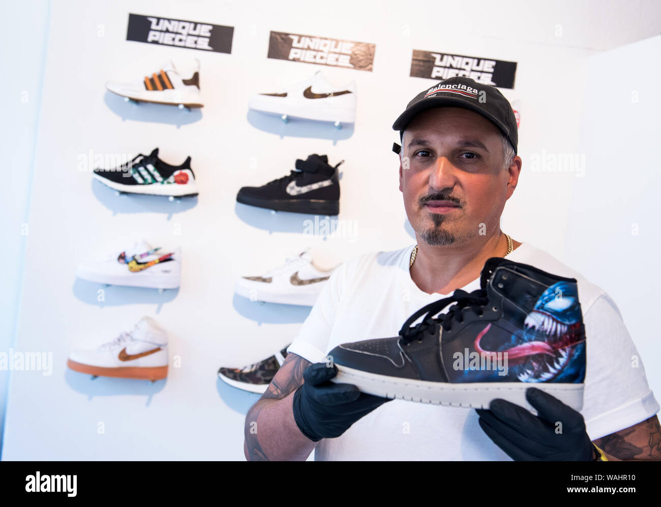 Hamburg, Germany. 30th July, 2019. Martin Olomi, founder of the manufactory  "Sneaker Surgery" presents a painted sneaker. The uplifting of sneakers of  the international sports shoe manufacturers is the order of the