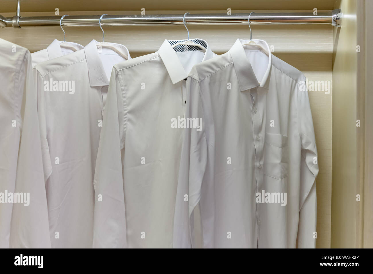 shirts hanging on clothing rack in an indoor closet Stock Photo