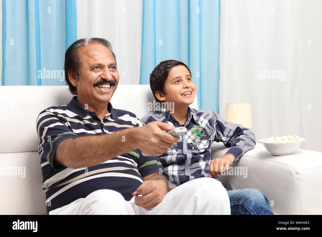 Old man with his grandson watching television Stock Photo